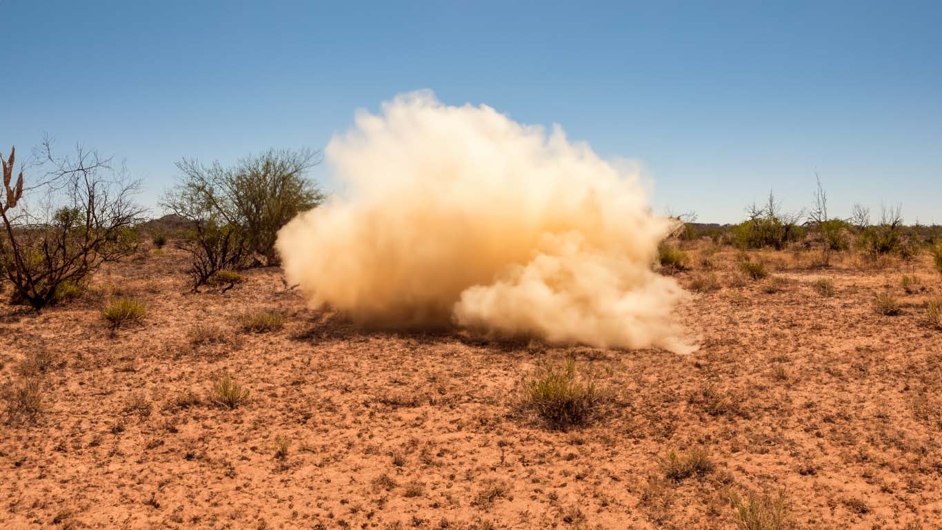 A Desert scene with a dust cloud, ominously not showing what in behind it.